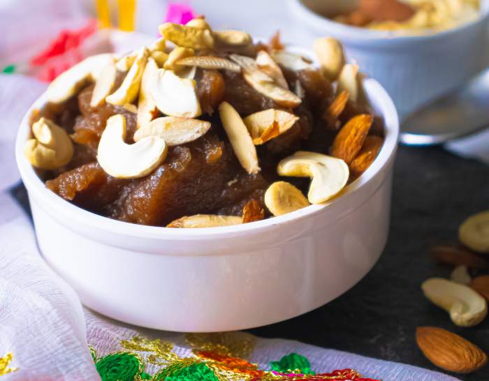 Closeup of halwa kept in a white bowl with nuts beside it