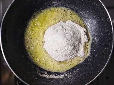 Flour added to ghee in a black skillet