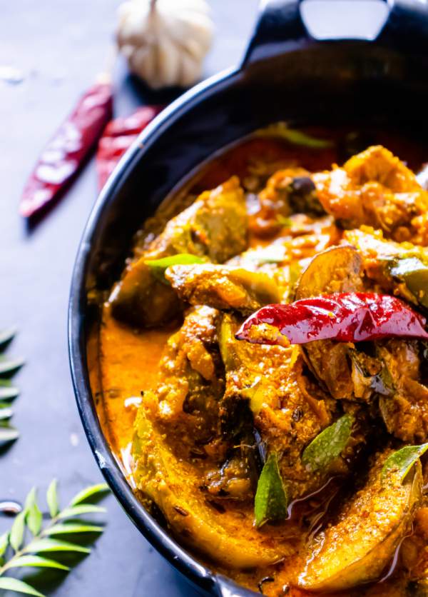 Bengali Dahi Baingan Recipe with curry leaves and red chilies beside