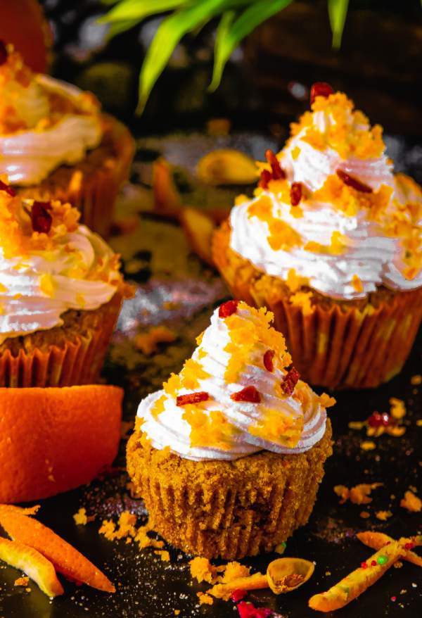 Orange Cranberry Cupcakes placed on a black background with Orange zest around 
