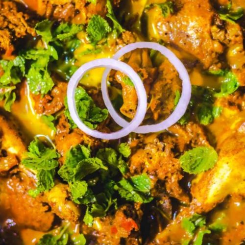 andhra chicken curry with onions rings and mint leaves